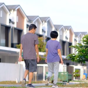 A man and woman walking down a street in Denver with houses behind them.
